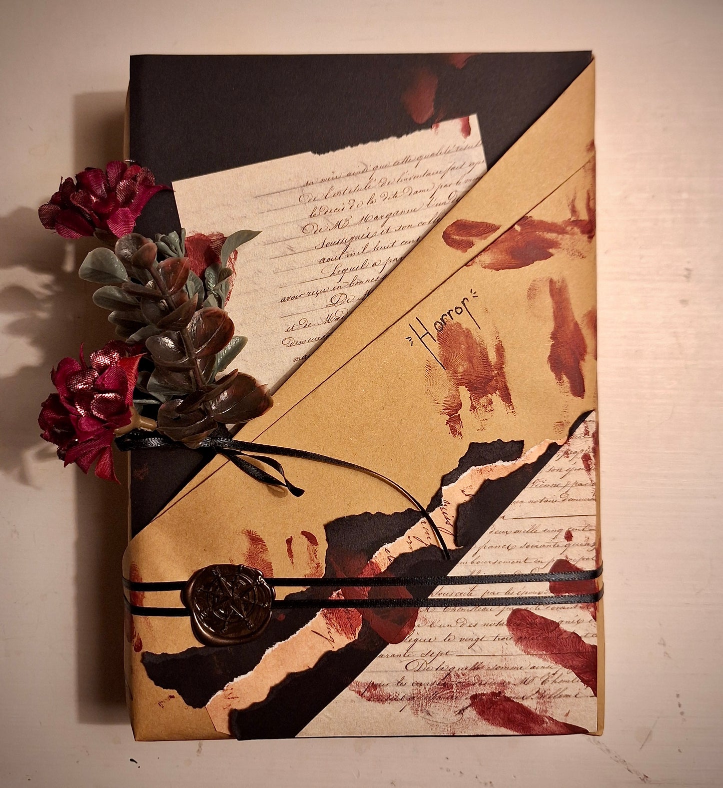Horror book wrapped with black and tan paper, and decorated to look like it has been smeared with bloody fingerprints.
